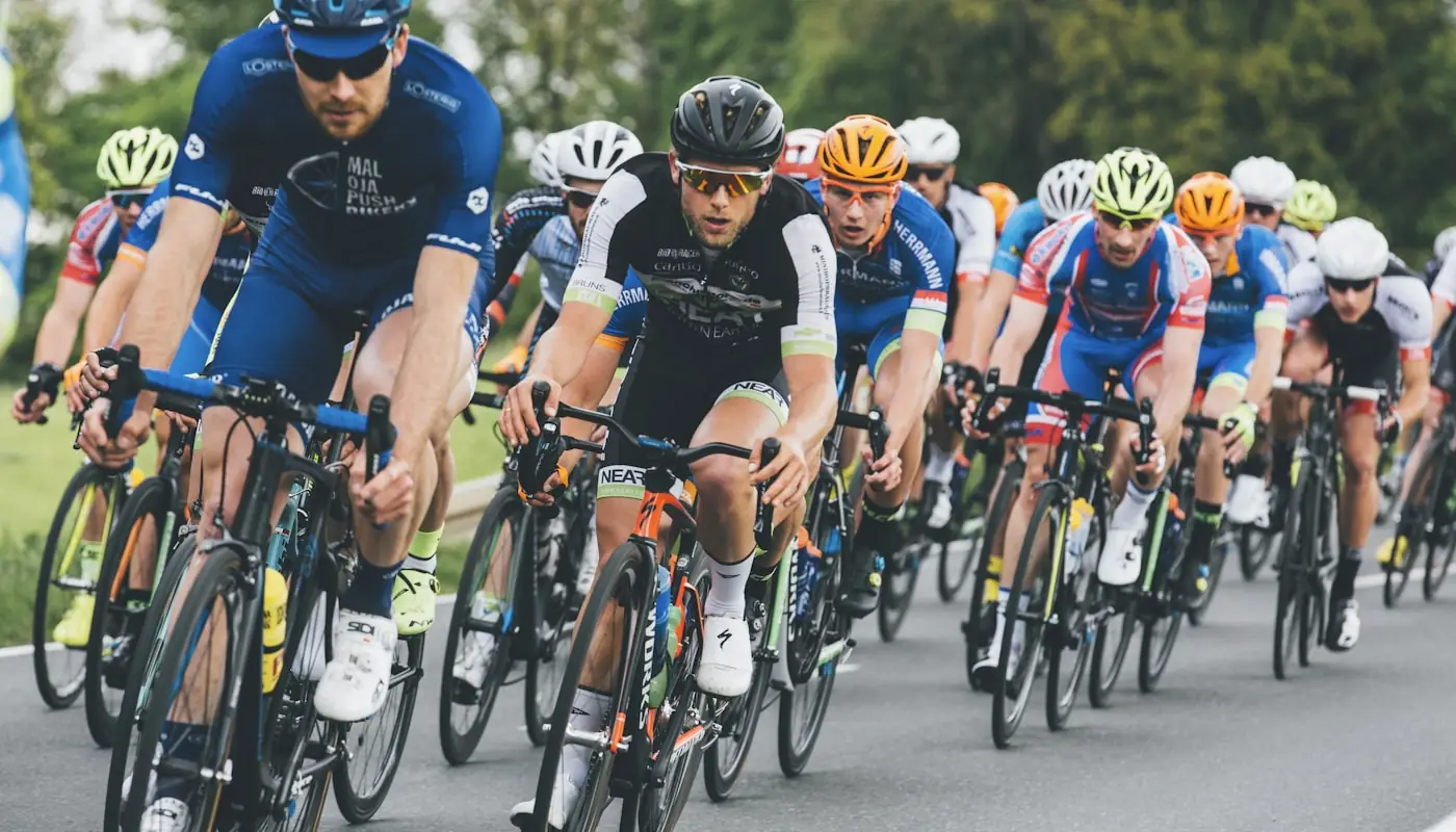 A tight group of cyclists riding together on an open road